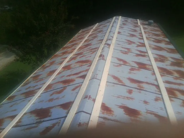 Rusted metal roof panels with new wood purlins before replacement — Storm Damage Roof Repair in Bazine by Roofing Brothers