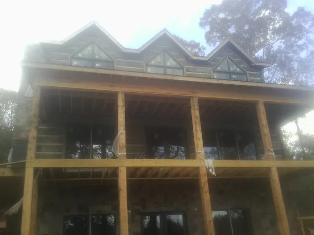 Dormers and porch framing on a large log home under construction — Roof Coating work by our crew in Bazine