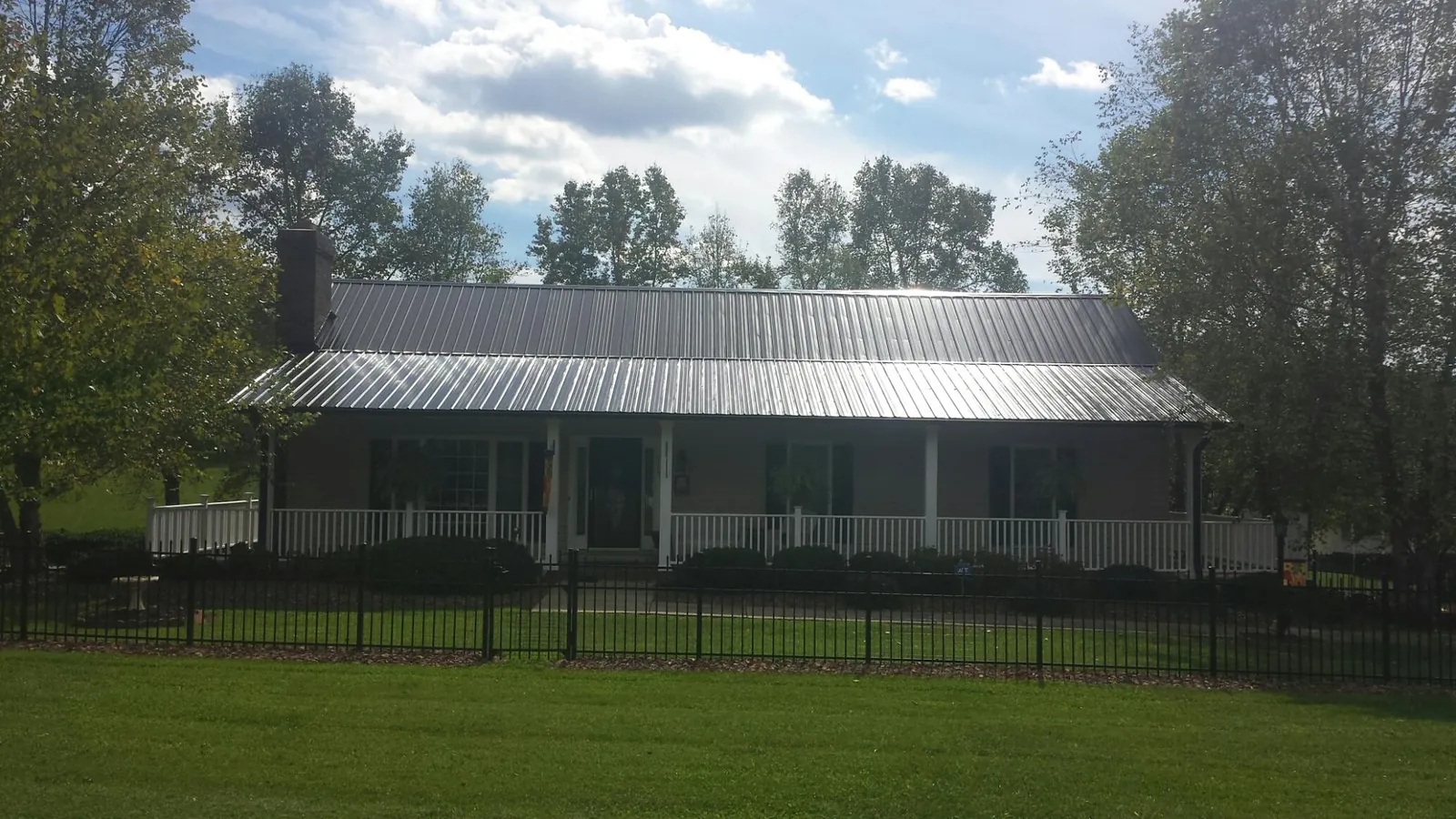 Gray metal roof on a brick ranch with a full width front porch — Gutter Guard Installation work by our crew in Bazine