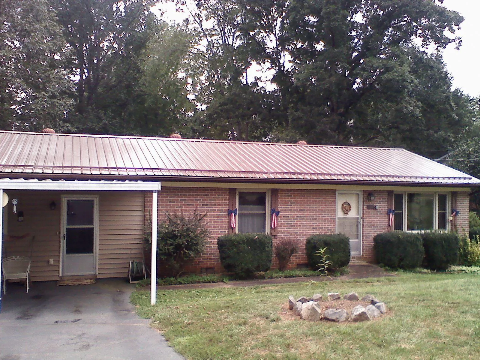 Bronze metal roof and carport on a brick ranch home — Roof Repair work by our crew in Bazine